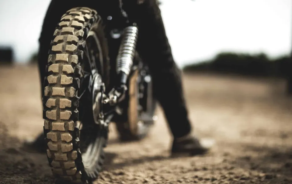 Motard assis sur un café racer, vu de dos