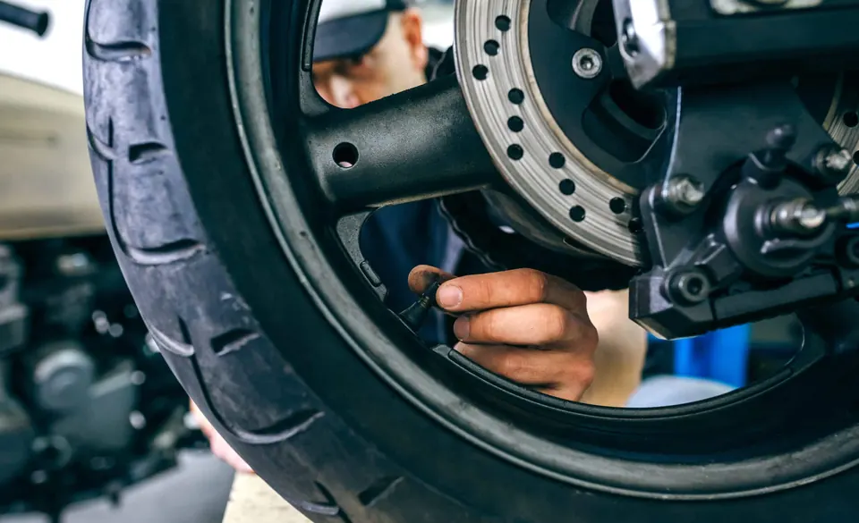 Mécanicien contrôlant la valve d’une roue de moto