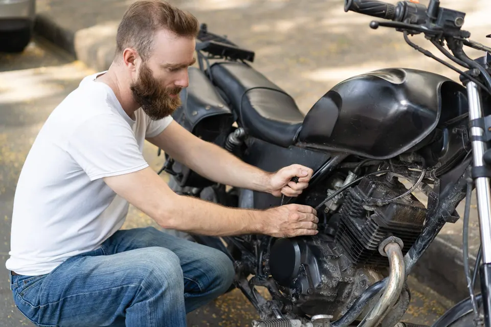 Motard tentant de redémarrer sa moto en panne