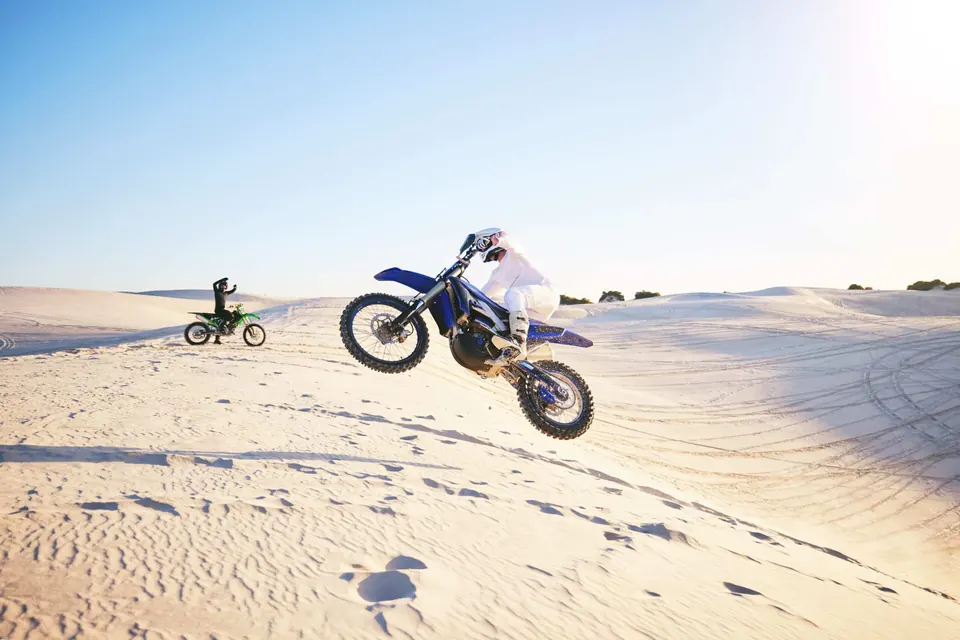 Pilote de moto tout-terrain en plein saut dans le désert